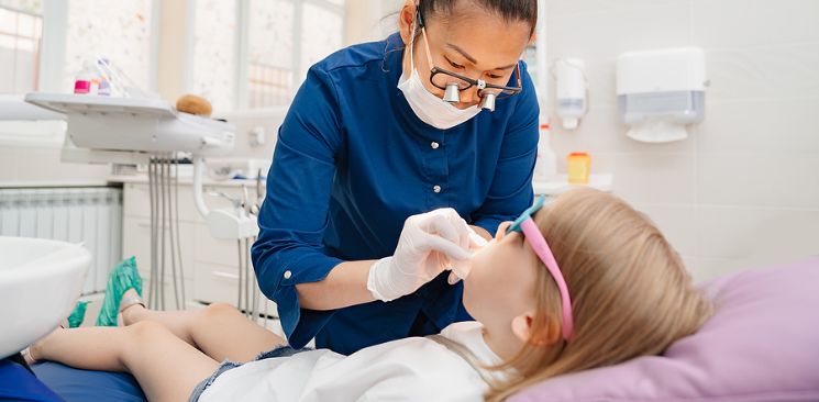 Dental Assistant Performing An Exam On A Young Patient