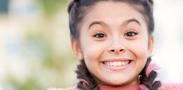 A Smiling Girl With Pink In Her Braids.