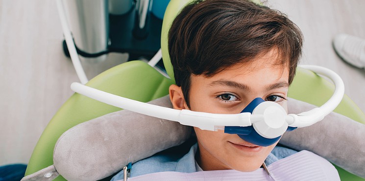 Photo of a boy at the dentist receiving laughing gas.