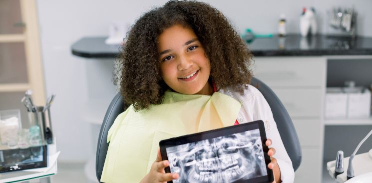 Young Girl Patient Holding A Dental X-Ray.